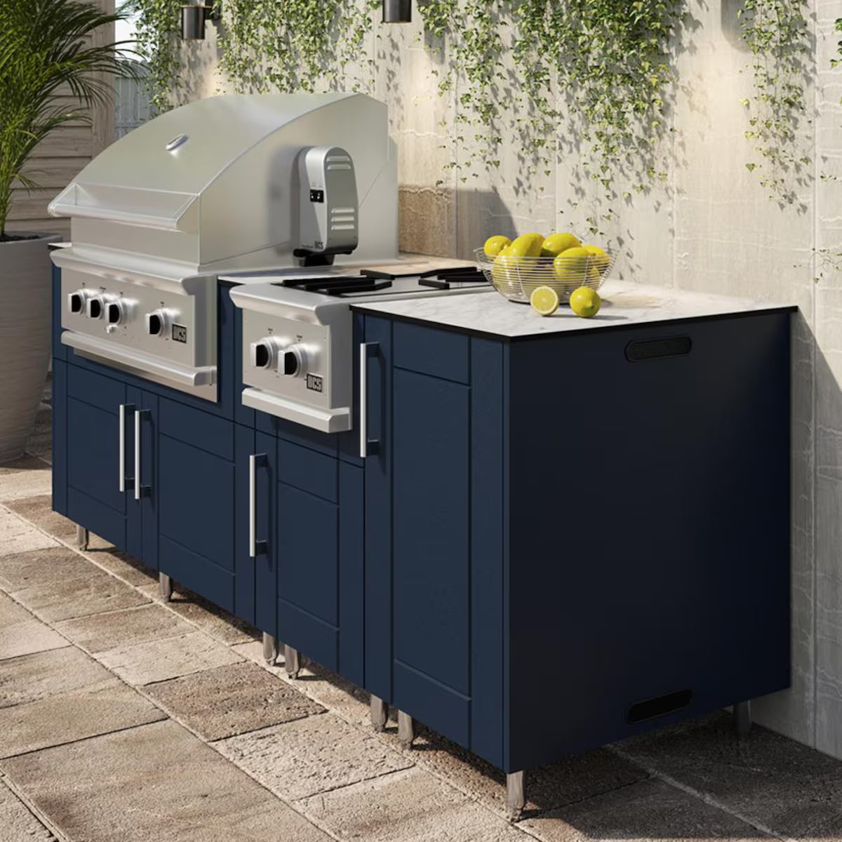 Outdoor kitchen with blue cabinets, white countertops, and a grill.