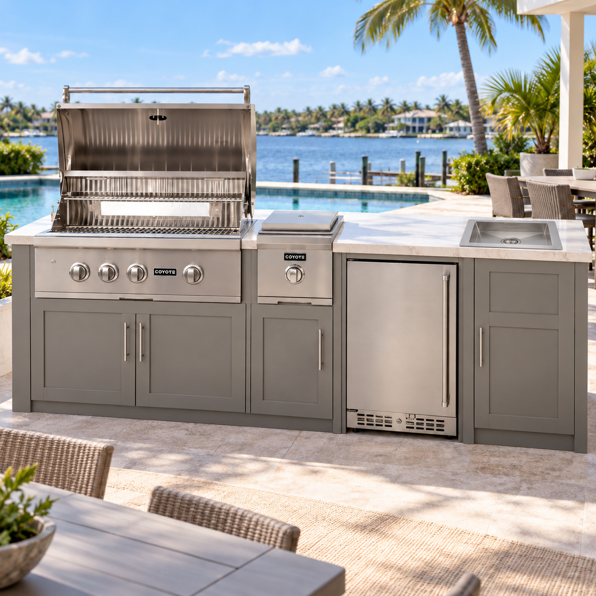 Coyote Cook & Entertain Package – 30" Grill, 24" Refrigerator, Single Side Burner & Drop-In Sink installed in an outdoor kitchen; cabinetry and setting shown for inspiration